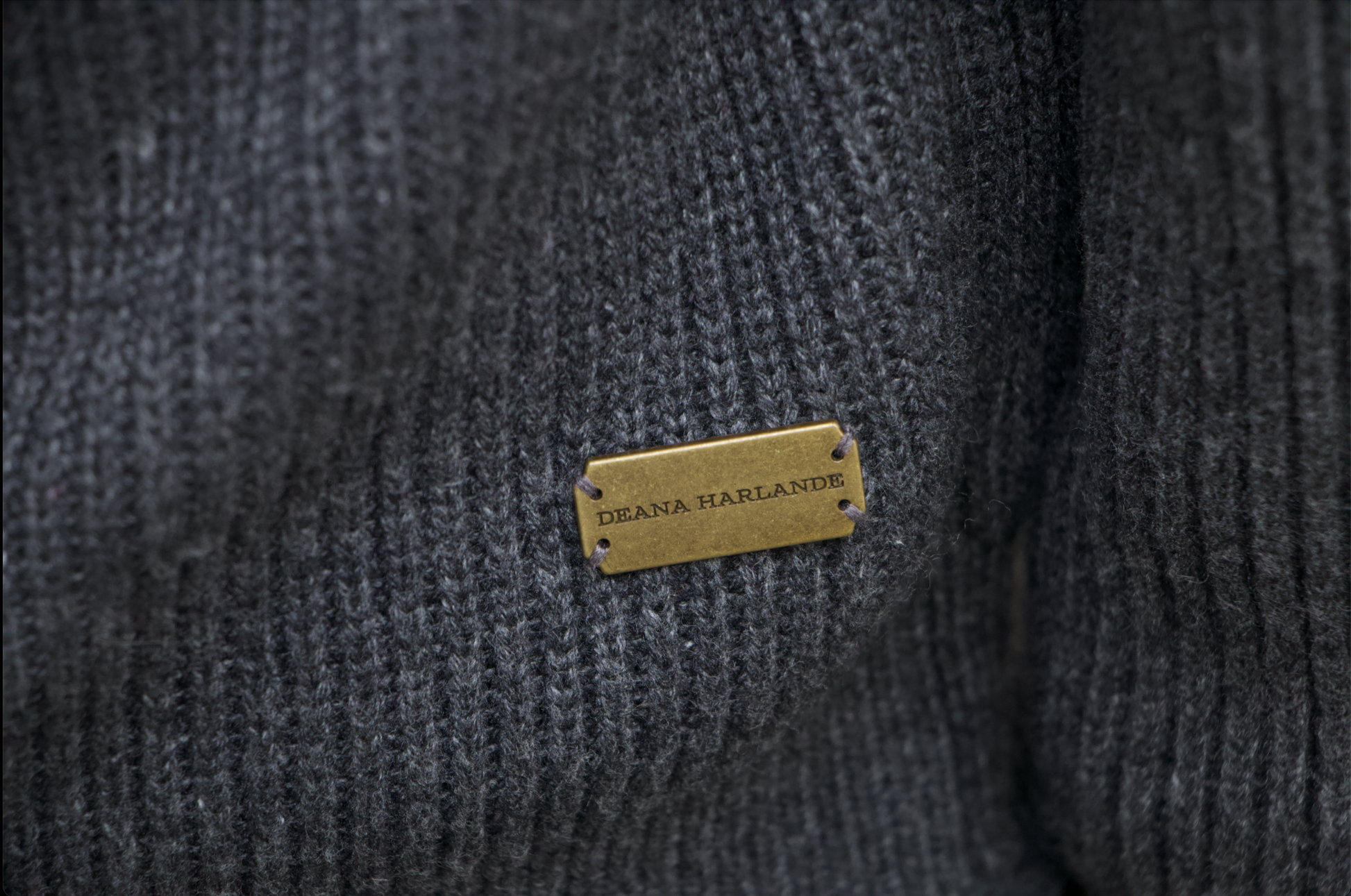Close-up of a textured gray yarn with a gold Deana Harlande label.